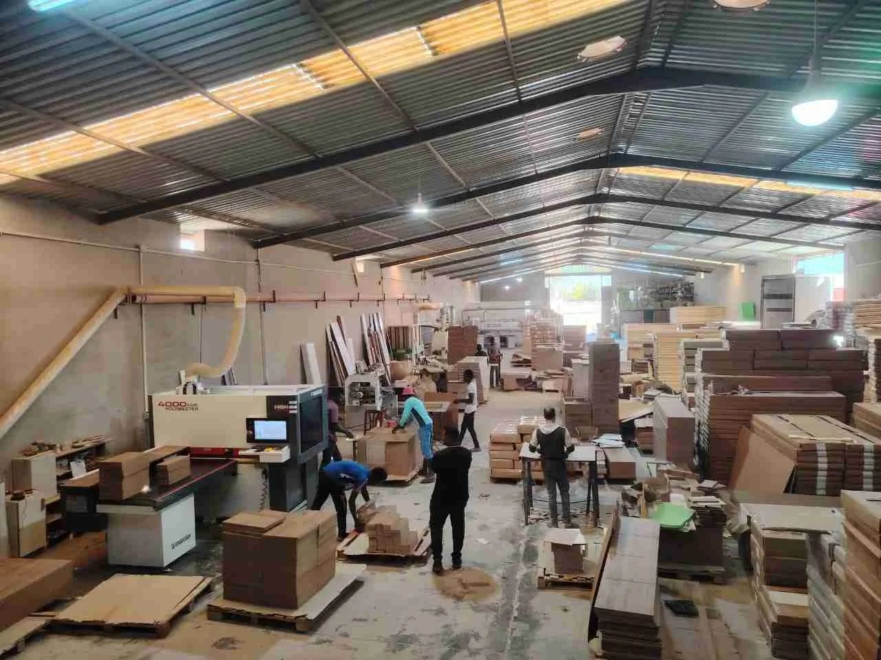 صالة الإنتاج في ورشة جبل أكاكوس، مع آلات وألواح مقطوعة وعمّال